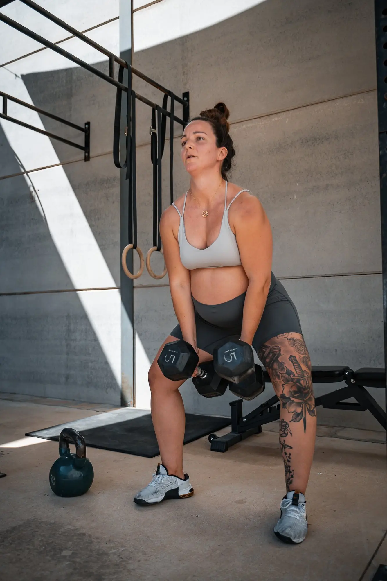 Pregnant athlete training with dumbbells in the gym